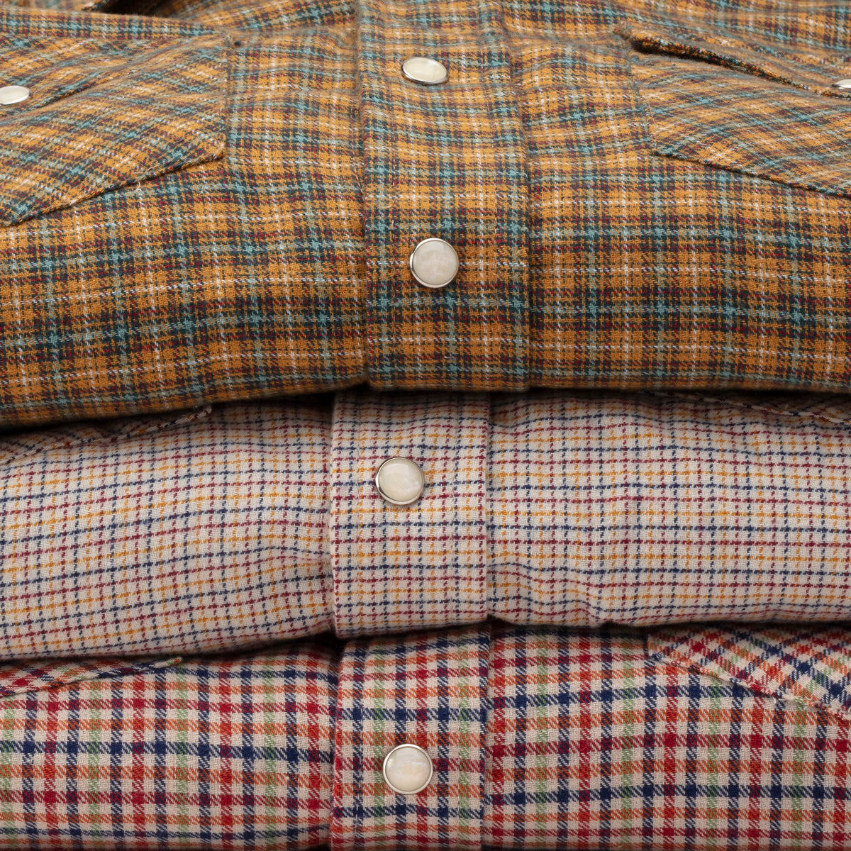 The three Hill Country Micro Flannels folded in a stack, mother-of-pearl snaps catching the light